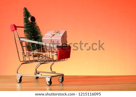 NEW YEAR CONCEPTUAL with shopping trolley,gift boxes and Christmas tree on a wooden table.