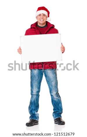 Full length portrait of a young man in winter clothing and Santa hat with empty white board isolated on white background