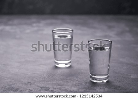 Two russian vodka shots on black table,selective focus.Vodka in shot glasses on black background
