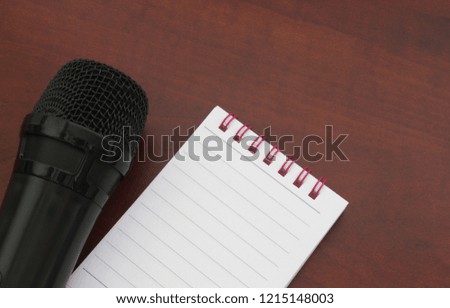 Microphone and blank notebook on wooden table