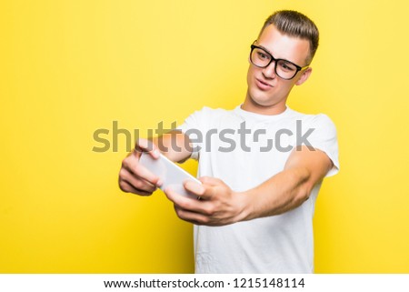 Portrait of a happy man taking a selfie isolated over yellow background