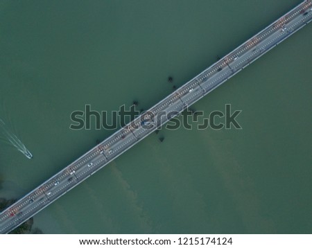 Aerial image of a bridge with some cars passing through. The bridge is connecting the main land with a small island in Kedah.