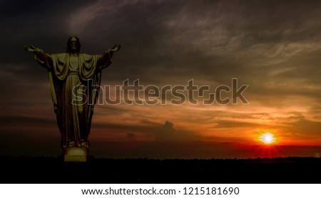 Jesus stood with his arms outstretched, illuminating the background of the sky with the sun falling.