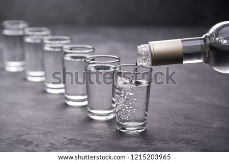 Pouring vodka into the glass on a black background, selective focus Royalty-Free Stock Photo #1215203965