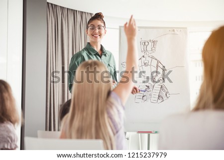 What is it. Happy teacher showing on picture. Girl rising hand up. She knowing answer