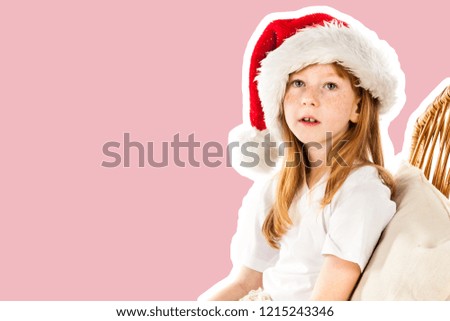 Little red haired and freckled face girl dressed in Santa's hat and covered by plaid blanket dreams about gifts. Christmas and New Year advertising concept. Magazine style fashion collage