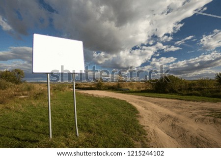 Information board on a sandy road with blue sky and white clouds