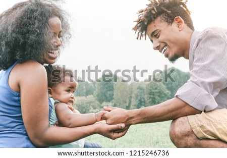 Happy family holding hands together in a park outdoor - Mother and father with their daughter enjoying a weekend day - Love and happiness concept 