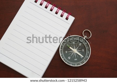 Round compass with blank notebook for text on table close up