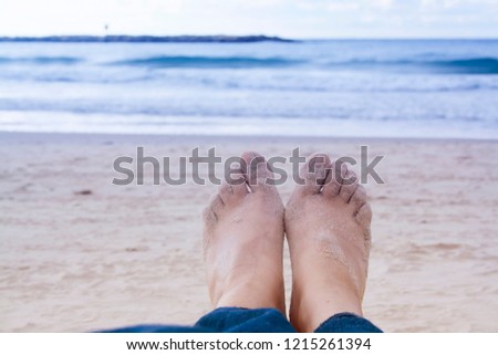 Girls legs close-up on the coast of Tel Aviv. Evening, beach and sea. Symbol of travel and vacation holidays.