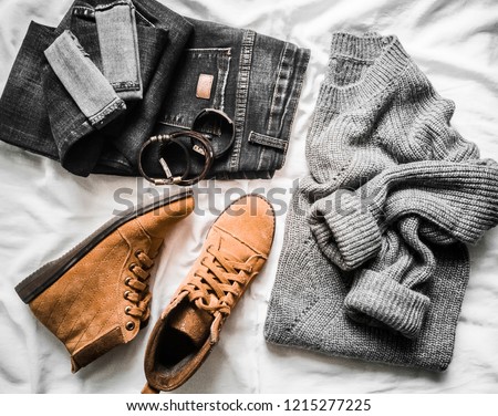Set of women's autumn, winter clothes on a light background - jeans, gray pullover oversize, suede brown boots and scarf. Fashionable clothes for walks, flat lay    
