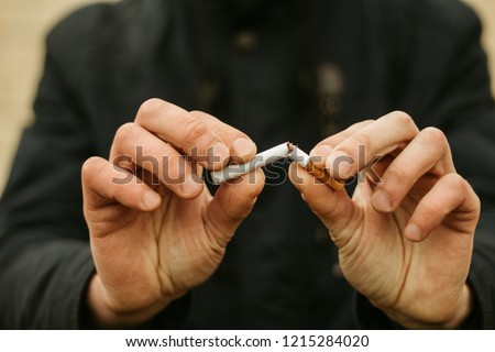 World No Smoking Day. The fight against nicotine addiction. The guy breaks a cigarette.