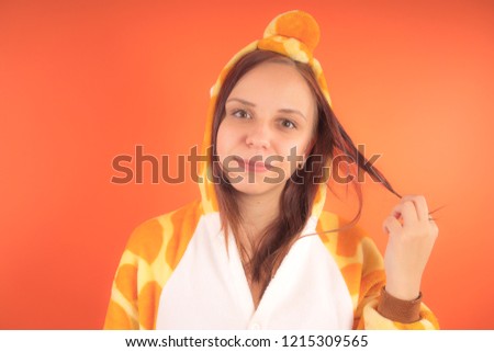pajamas in the form of a giraffe. emotional portrait of a girl on an orange background. crazy and funny woman in a suit. animator for childrens parties

