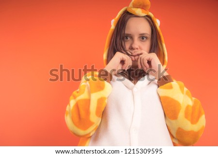 pajamas in the form of a giraffe. emotional portrait of a girl on an orange background. crazy and funny woman in a suit. animator for childrens parties
