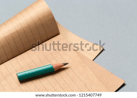 Short worn pencil with notepad on gray desk