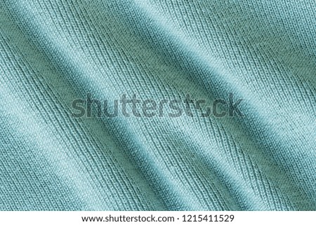 Knitted green fabric texture with large diagonal fold