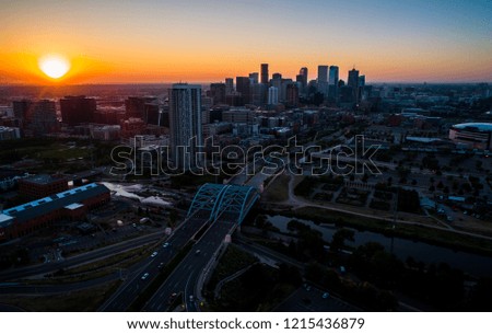 dramatic sun bursts above horizon during Morning Sunrise in the Mile High City of Denver , Colorado , USA golden hour Traffic and gorgeous sunshine aerial view Skyline Cityscape above River Bridge