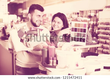 Young couple of customers checking color scheme in paint supplies shop