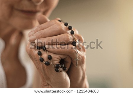 Old wrinkled hands holding a rosary. Closeup of christian senior woman hands holding rosary beads and crucified cross while praying God. Mature catholic lady holding black rosary and praying. Royalty-Free Stock Photo #1215484603