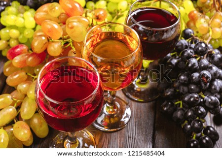 wine with branches of white grapes. On a wooden table.