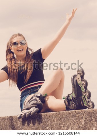 Young woman wearing roller skates outdoor. Fashionable fit girl having fun resting at sunny summer day.