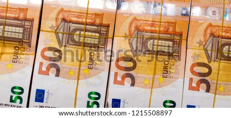 Pile of 50 real euro notes 50-euro banknotes under rubber band, isolated on black background. About 2500 euros worth