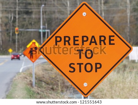 A road construction sign warns oncoming traffic and motorists/Prepare to Stop Sign/A construction sign warns motorists to prepare to stop.