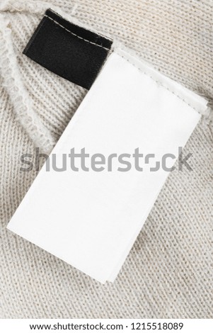 Blank black and white clothes label on grey knitted background