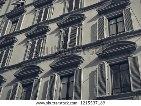 Retro photo of a building with windows and window shutters. Historical architecture of European cities. Vintage. West European style. Black and White Photography