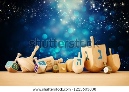 Banner of jewish holiday Hanukkah with wooden dreidels (spinning top) over glitter shiny background Royalty-Free Stock Photo #1215603808