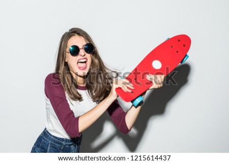 Portrait of woman in sunglasses beat and scream with skateboard over white background