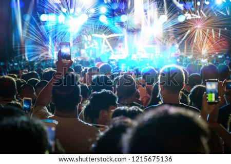 Concert crowd of Music fanclub hand holding mobile smart phone taking video record or Live stream with super star songer and celebrate with fireworks, happy new year and christmas concept