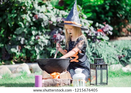 Adorable little girl wearing witch costume on Halloween at autumn day and having fun outdoors. Trick or treat.
