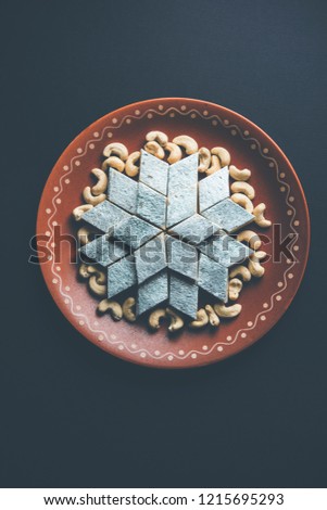 Kaju Katli is a Diamond shape Indian sweet made using cashew sugar and mava, served in a plate over moody background. selective focus