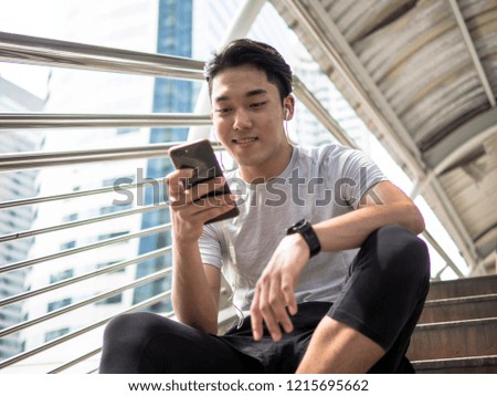 young teenage boy spending time at the city park, listening to music with headphones