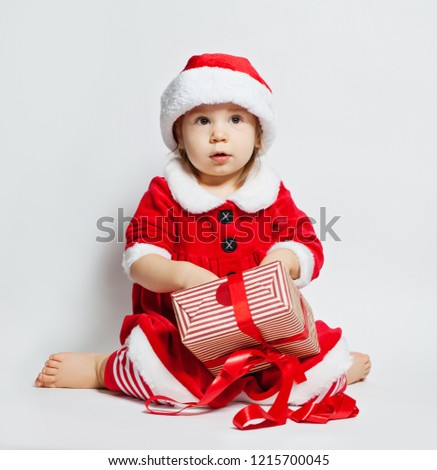 Christmas child in Santa hat opening Xmas gift box on white background