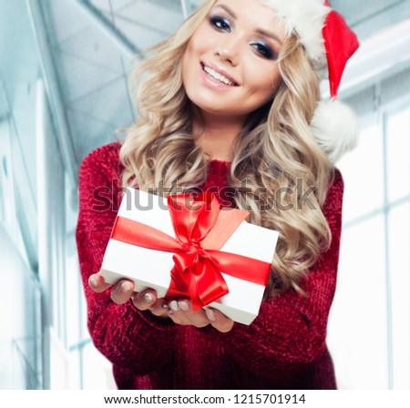 White christmas gift box with red silky ribbon in hands of happy Christmas woman on office background