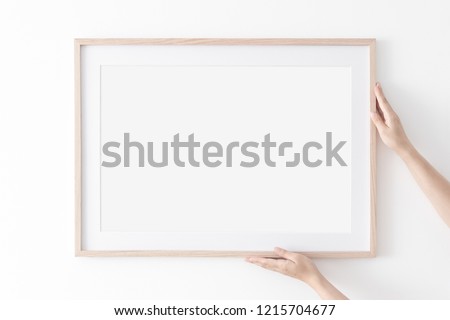 Landscape large 50x70, 20x28, a3,a4, Wooden frame mockup with passe-partout on white wall in women hands. Poster mockup. Clean, modern, minimal frame. Empty fra.me Indoor interior, show text or