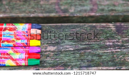 Coloured pencils or crayons loosely arranged isolated on old wooden background.