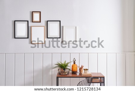 Working table and wooden desk style with many frame on the white wall.