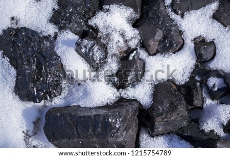 Pile of black coal covered with white snow. Winter heating. Energy supply security. Closeup. Selective focus Royalty-Free Stock Photo #1215754789