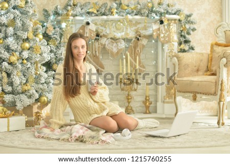 Portrait of a beautiful young woman with laptop near Christmas tree