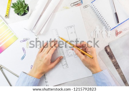 Architect drawing architectural project. Top view on unrecognizable designer hands working with building blueprint, copy space