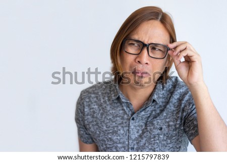 Nerdy Asian guy fooling at camera. Closeup of young man in casual touching eyeglasses, looking away and grimacing. Crazy face concept