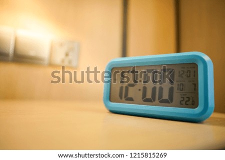 Digital alarm clock stands on a bedside table in the room or hotel room. Time management concept.