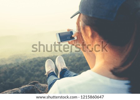 Asian woman travel to the top of the mountain and going to take picture of her feet with scenery by smartphone