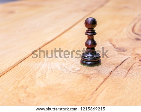 Pawn chess game board brown black white intelligence strategic pieces. Win piece board wood table.  Challenge outside sunny break.  Ready start standing. Battle checkmate. 