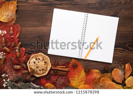 autumn leaves, cookies and paper notebook on wooden background with copy space for text, top view. flat lay