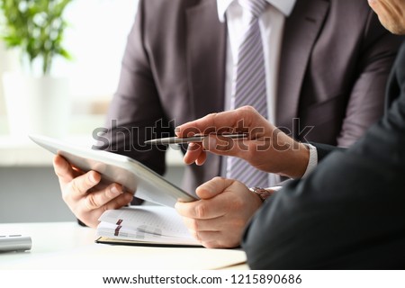 Two businessman are looking and studying statistics on tablet display closeup. Male hand opponent holds pen and points out problem collaboration business coach cooperation partnership palm concept Royalty-Free Stock Photo #1215890686