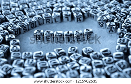 Belief - Word from Metal Blocks on Paper - Concept Photo on Table
